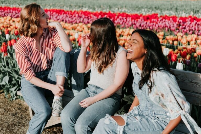 friends sitting wooden bench by the tulip flower field