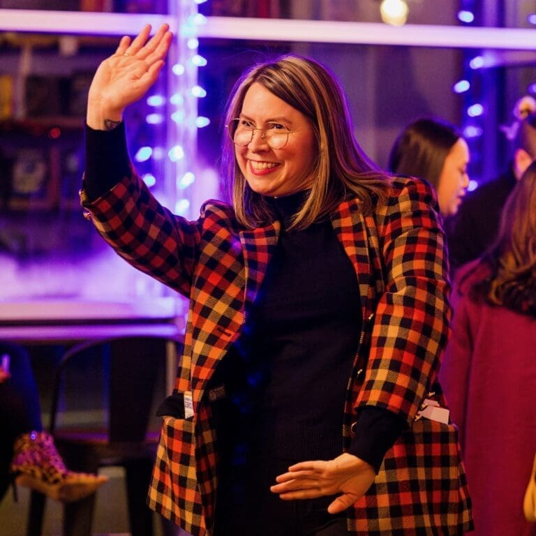 Woman wearing a blazer waving at another person