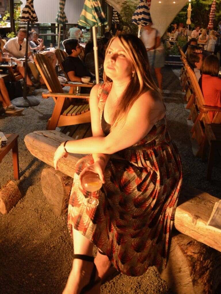 woman sitting alone by a fire with a cocktail