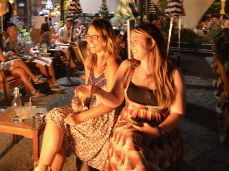 two women laughing sitting by a fire